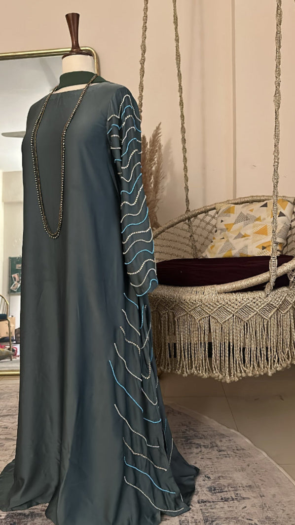 Long dark green dress with white embroidery on a mannequin against a neutral background.