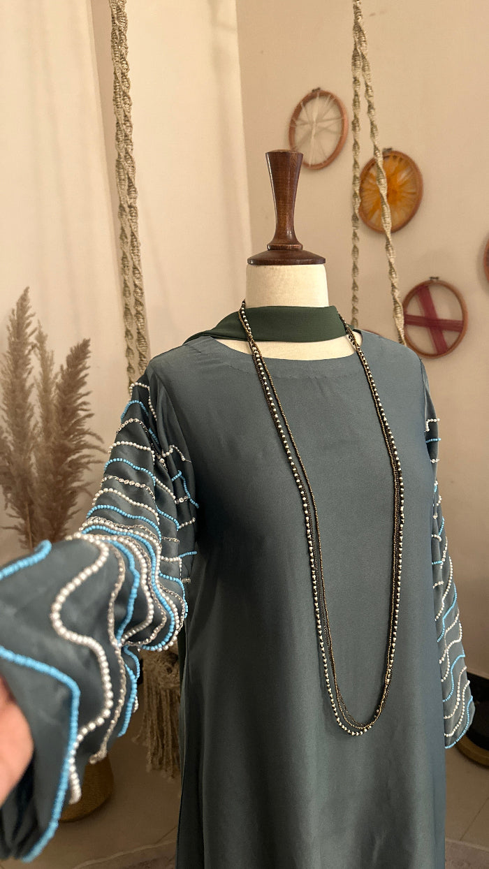 Mannequin wearing a gray outfit with a white shirt in a room with decorative items on the wall.