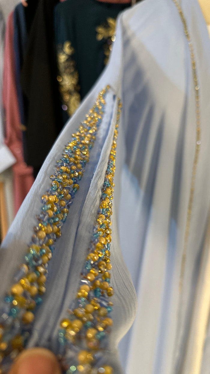 Close-up of a decorative ribbon with gold and blue beads on a white background.