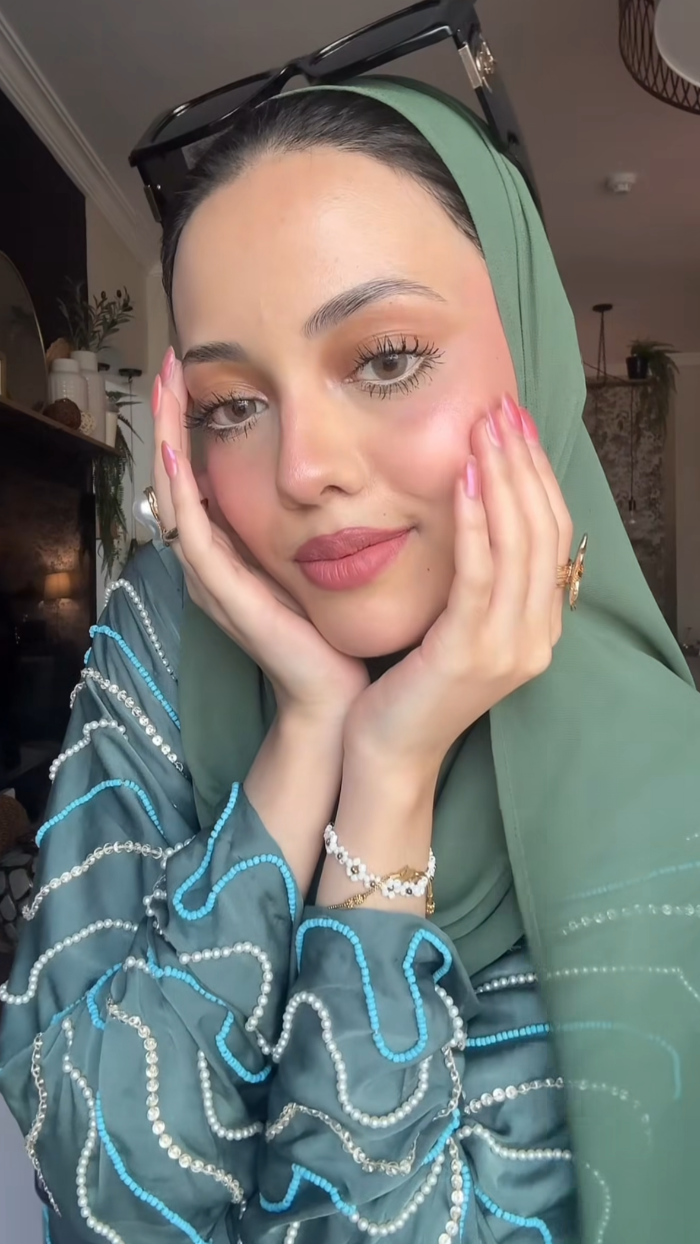 Woman wearing a green hijab with decorative patterns, indoors.