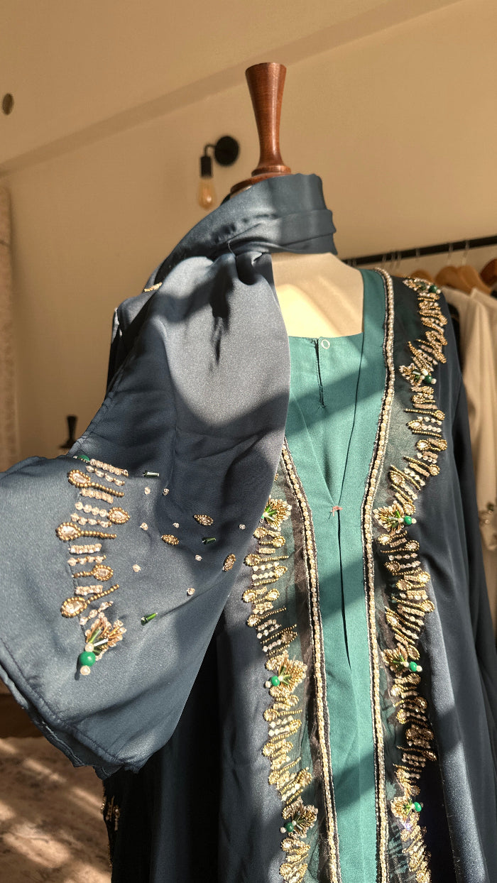 Decorative fabric with gold embroidery held by a hand against a neutral background