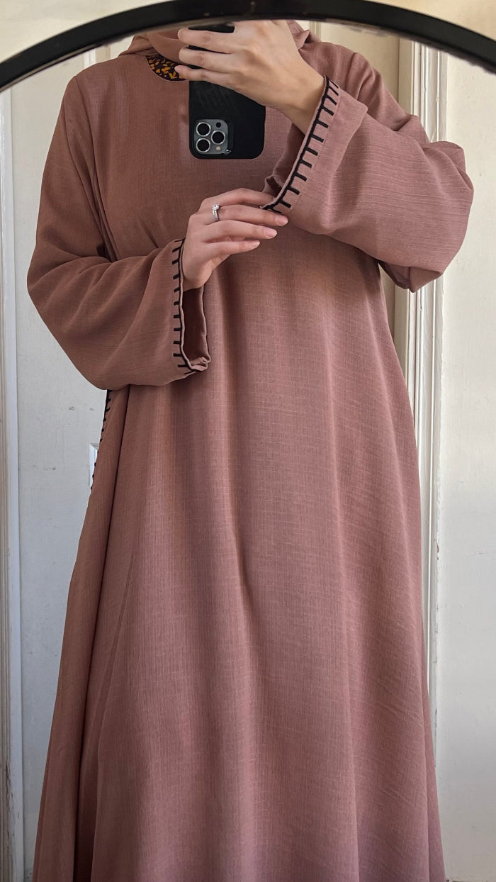 Person wearing a long brown dress taking a mirror selfie.