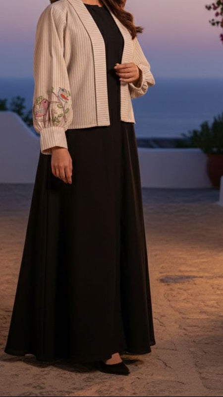 Woman in a black and white outfit standing in a scenic outdoor setting with flowers and plants.