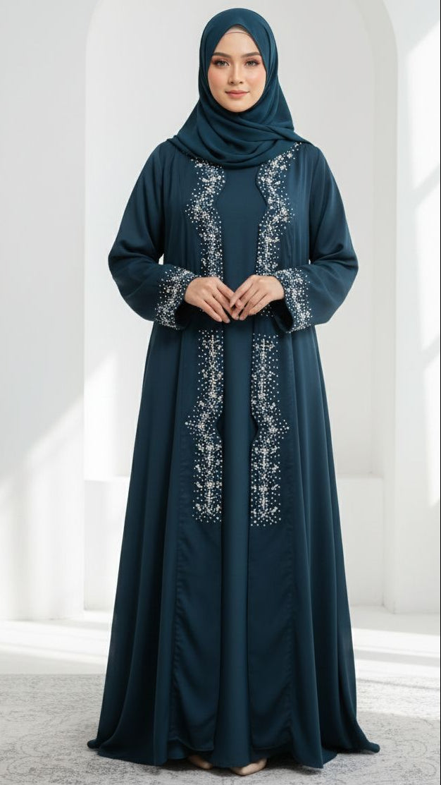 Woman wearing a dark blue abaya with white embroidery in a white architectural setting