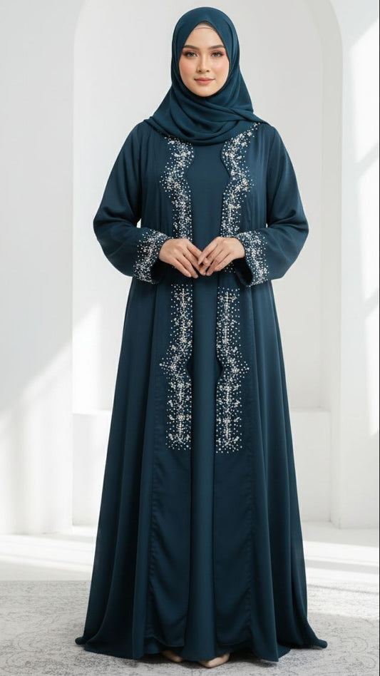 Woman wearing a dark blue abaya with white embroidery in a white architectural setting