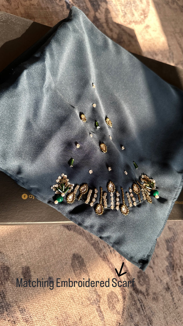 Gray embroidered scarf with intricate designs on a textured surface