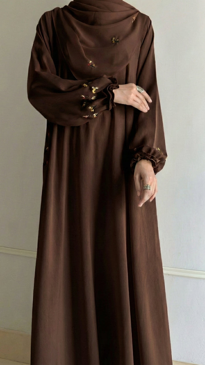 Brown long dress with gold buttons on a neutral background