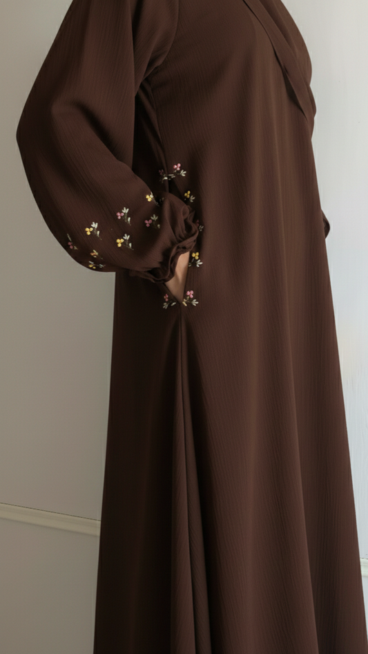 Brown abaya with floral embroidery on a white background