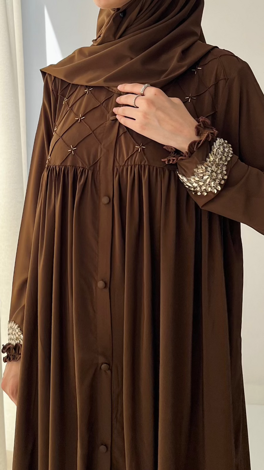 Brown dress with embellished sleeves against a neutral background