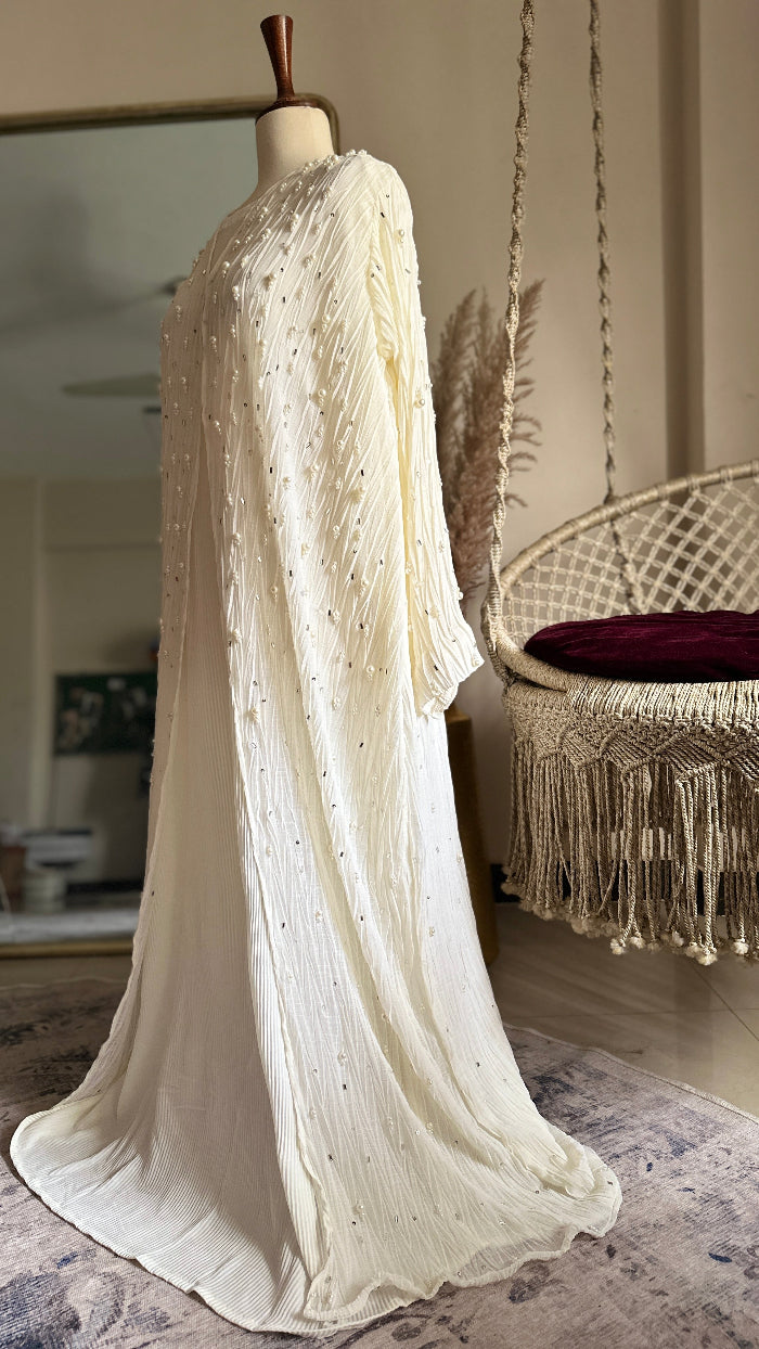 Mannequin wearing a long, flowing white dress in a room with a chair and decor.