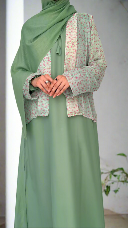 Person wearing a green dress with a floral patterned top against a plain background