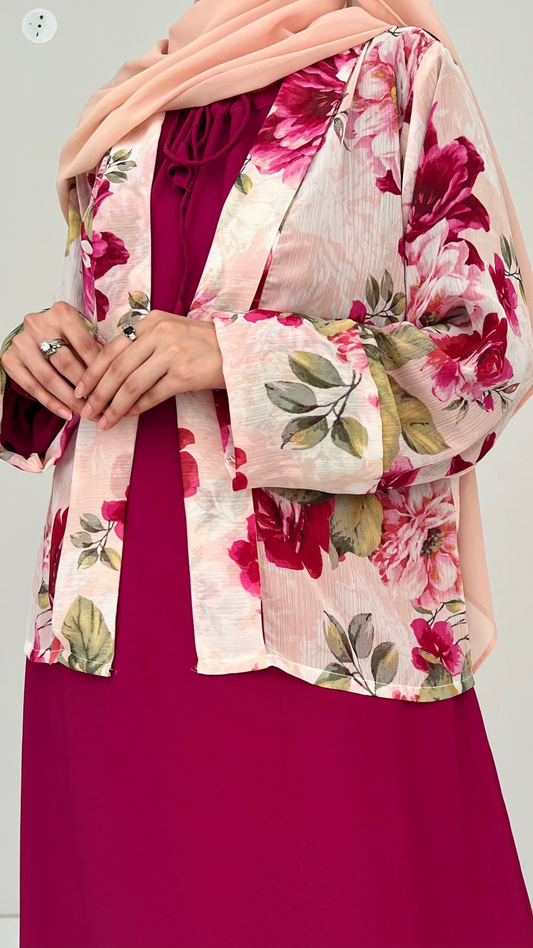 Woman wearing a floral jacket over a burgundy dress on a plain background