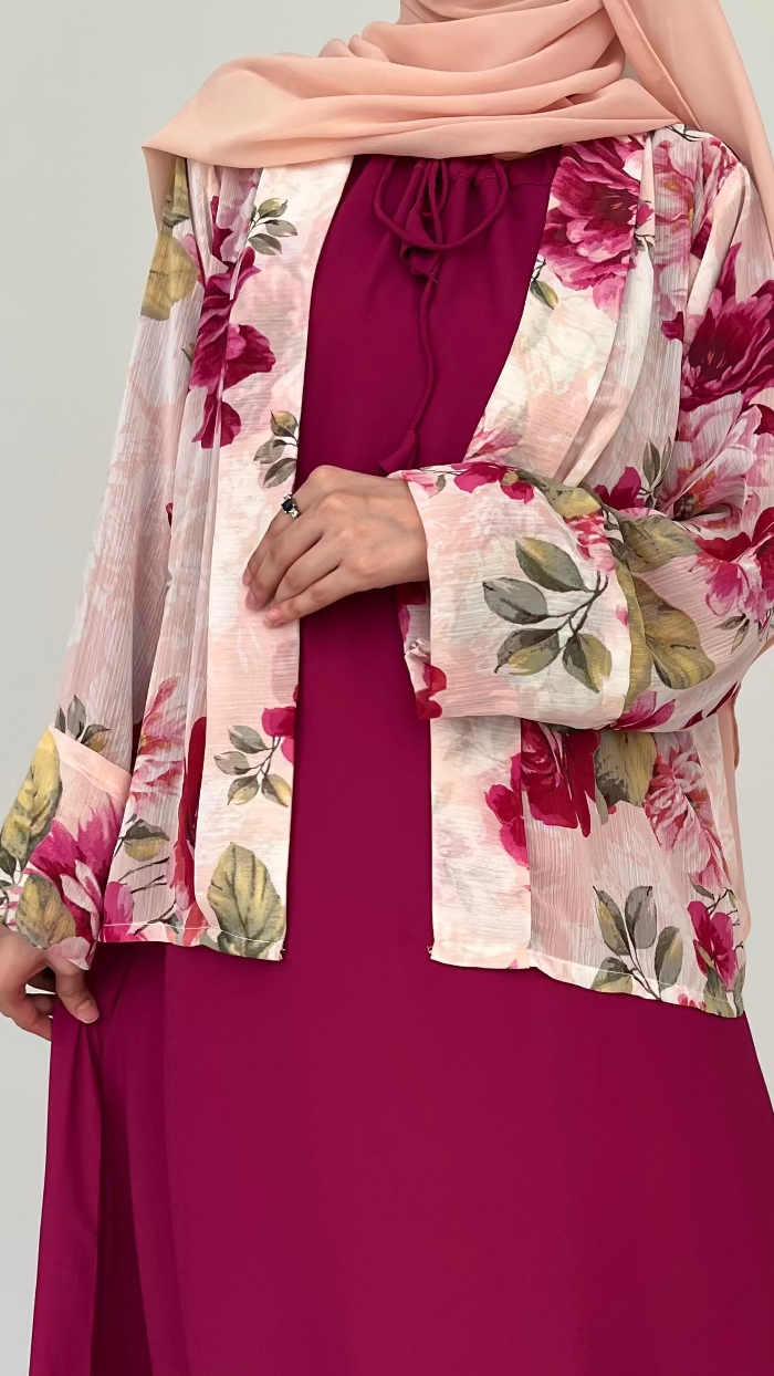 Woman wearing a floral kimono over a burgundy dress on a light gray background