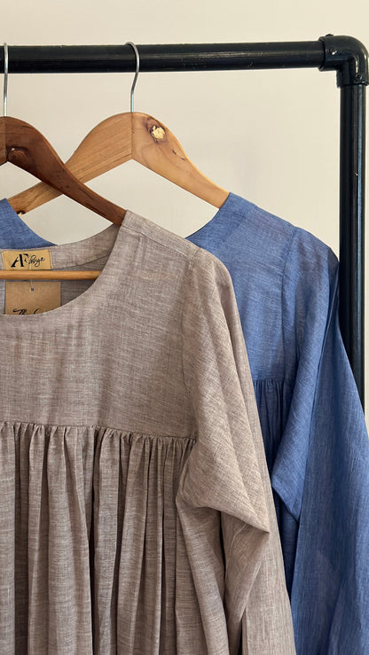 Person wearing blue pants and brown shoes standing next to a rack with gray pants.