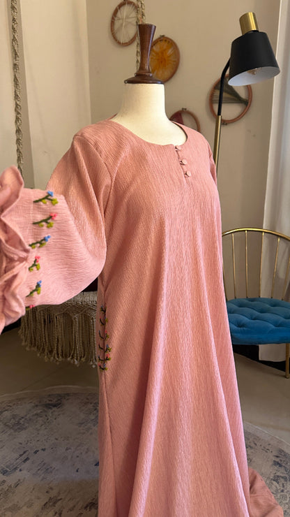 Pink dress with floral embroidery on a mannequin in a room setting.