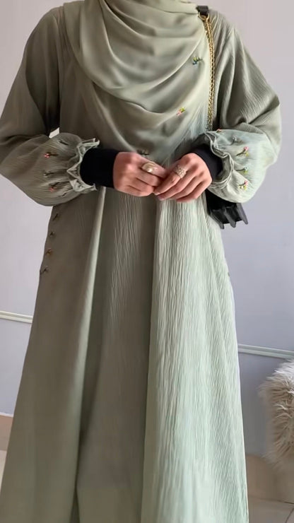 Long olive green dress with lace details on sleeves against a plain background