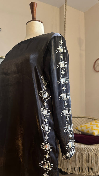 Black clutch bag with decorative patterns on a stand in a store setting
