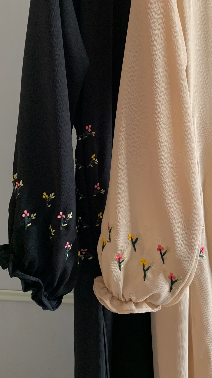 Black and beige garments with floral embroidery on a plain background