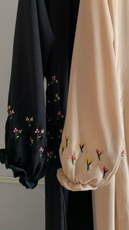 Black and beige garments with floral embroidery on a plain background