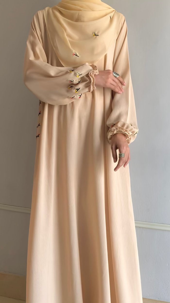 Beige long dress with floral embroidery on a plain background