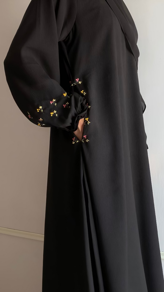 Black abaya with floral embroidery on cuffs against a neutral background