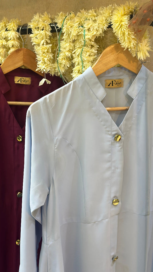 White shirt on a mannequin with gold buttons against a decorative background