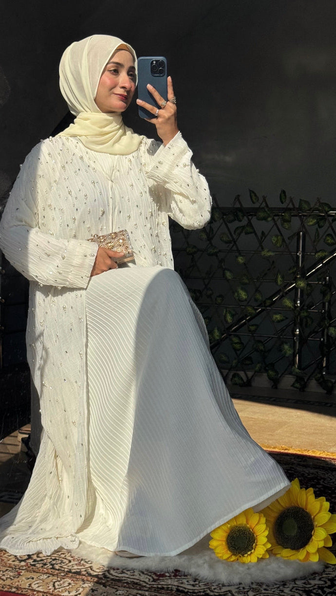 Woman in a white traditional outfit taking a selfie outdoors.