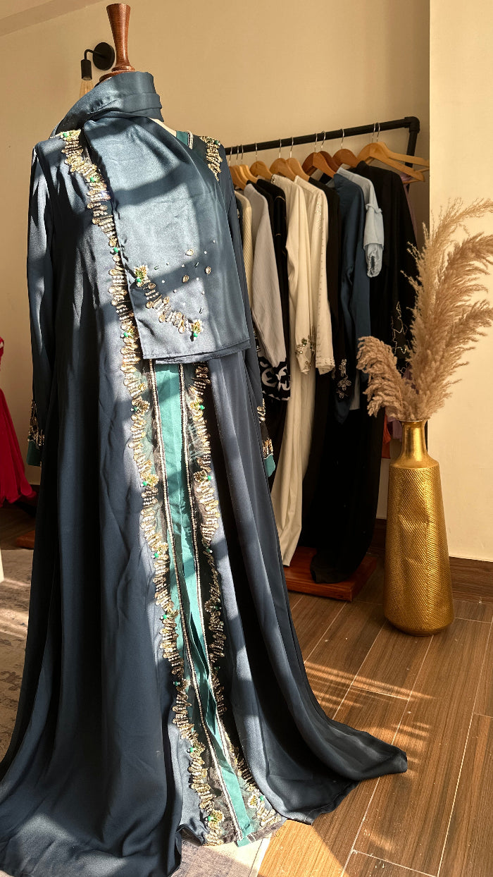 Black dress with gold embellishments on a mannequin against a neutral wall.