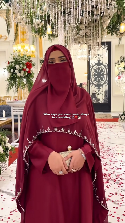 Woman in a red abaya with floral decorations and a clock in the background