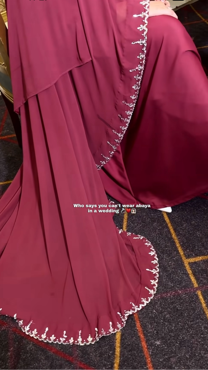 Maroon abaya with white embroidery on a tiled floor