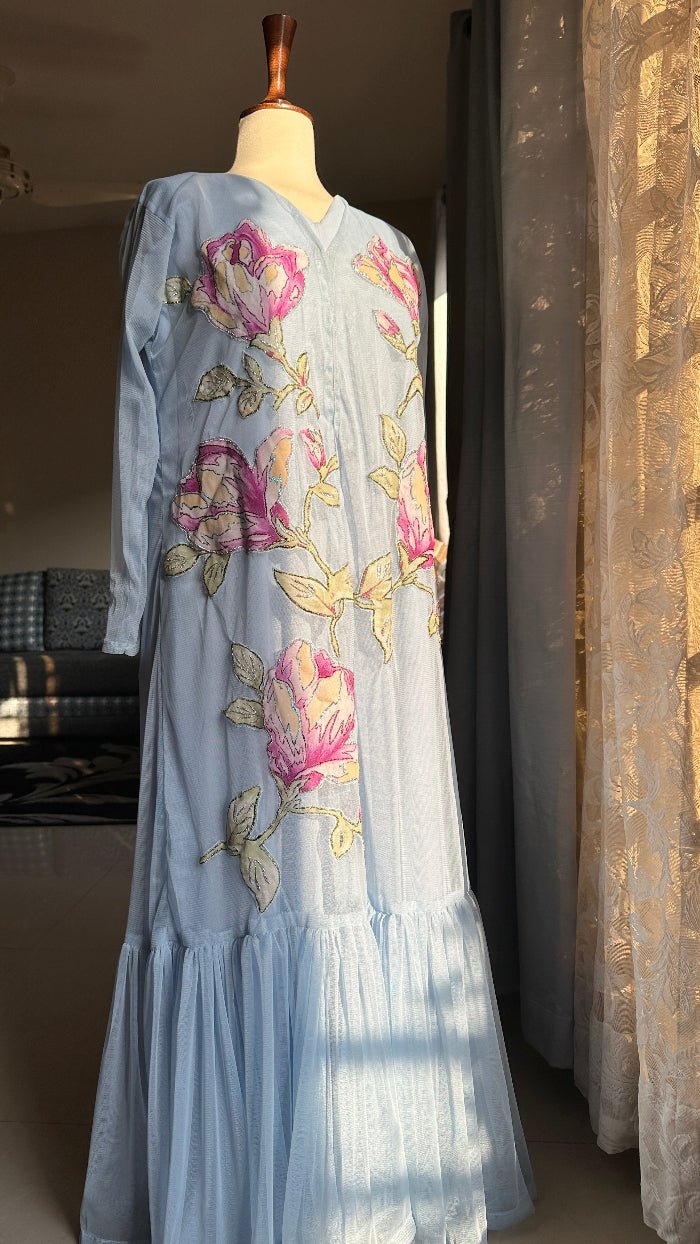 Embroidered dress on a mannequin with floral patterns in a room setting.