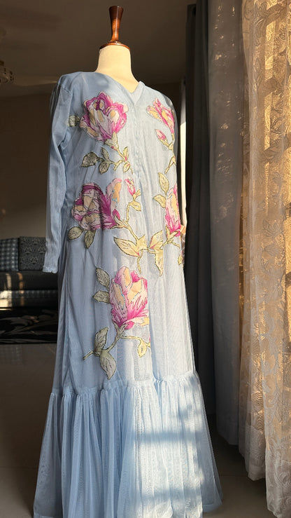 Embroidered dress on a mannequin with floral patterns in a room setting.