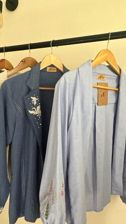 Stack of folded blue jeans on a rack against a beige wall.