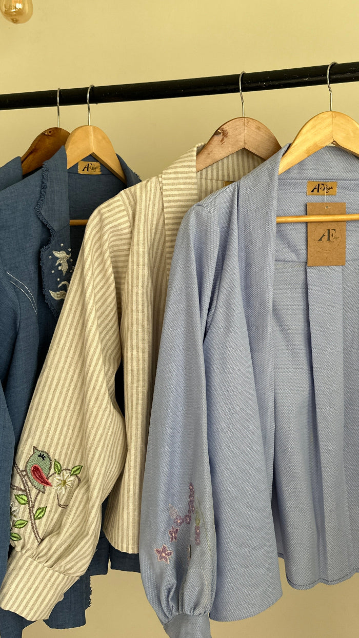 Stack of folded clothes on a wooden rack against a beige wall.
