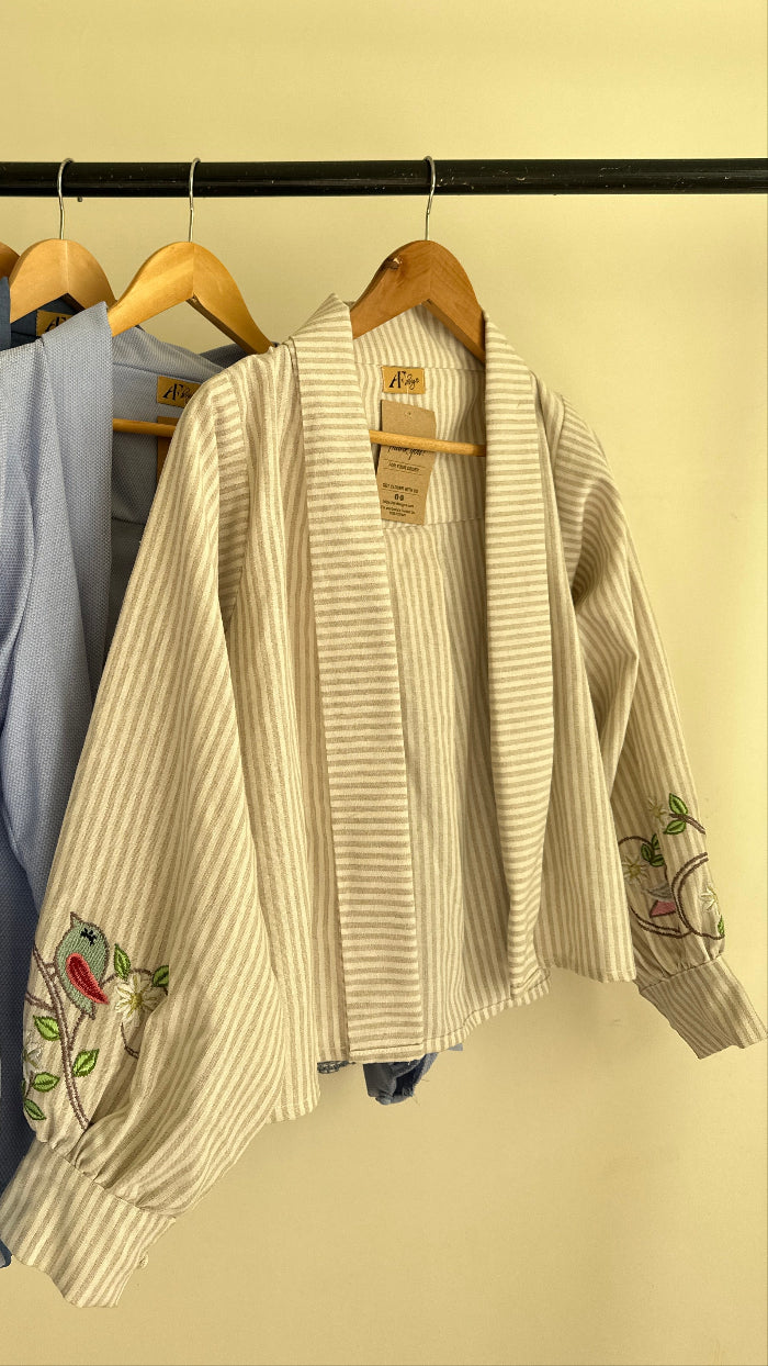 Stack of folded clothes on a wooden hanger against a beige wall.