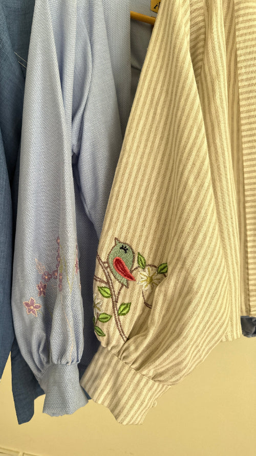 Stack of folded fabric pieces with embroidery on a beige background