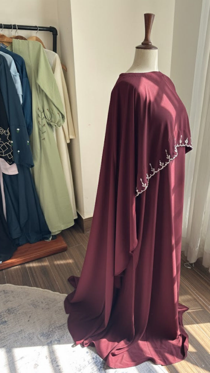 Maroon dress on a mannequin with a blurred background of clothes and curtains