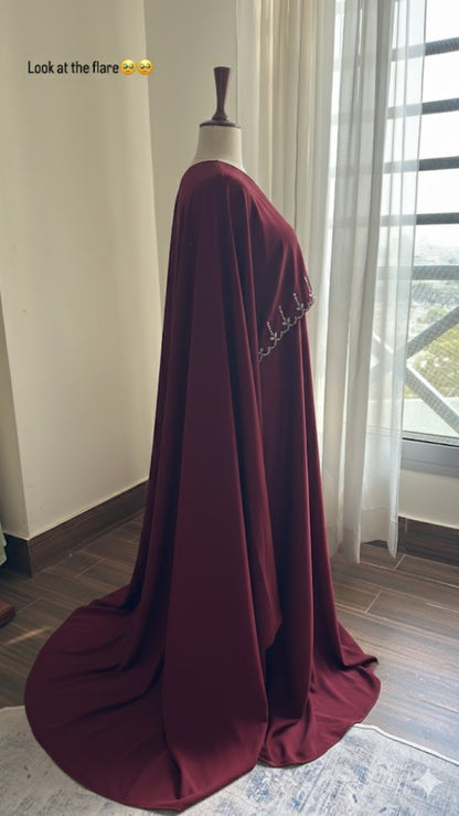 Maroon evening gown on a mannequin in a room with large windows.
