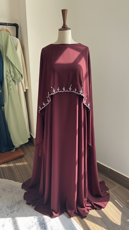 Burgundy dress with embellishments on a mannequin against a neutral wall.