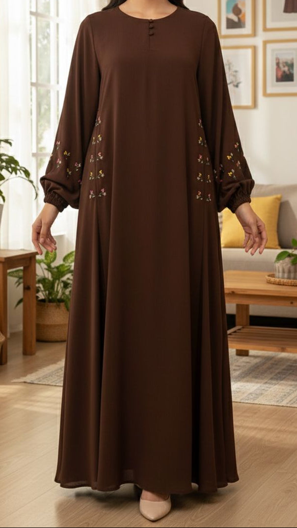Woman wearing a brown dress with floral embroidery in a living room setting