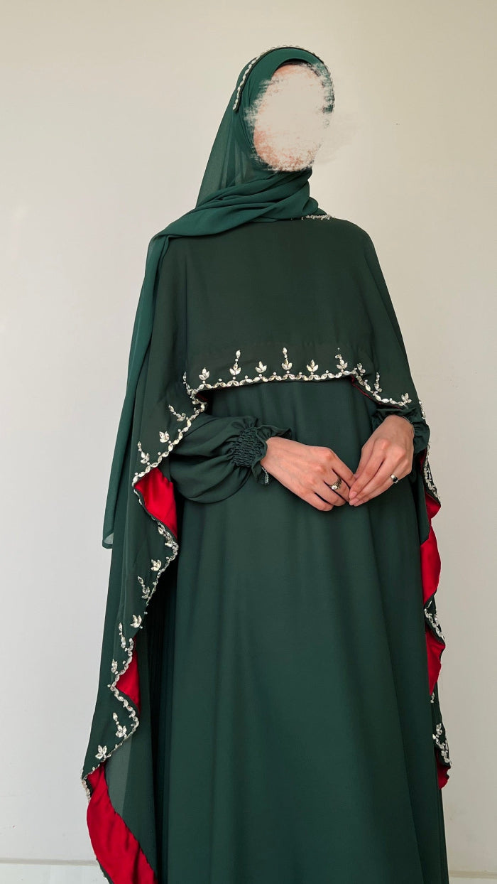 Green abaya with red accents and white embroidery on a plain background