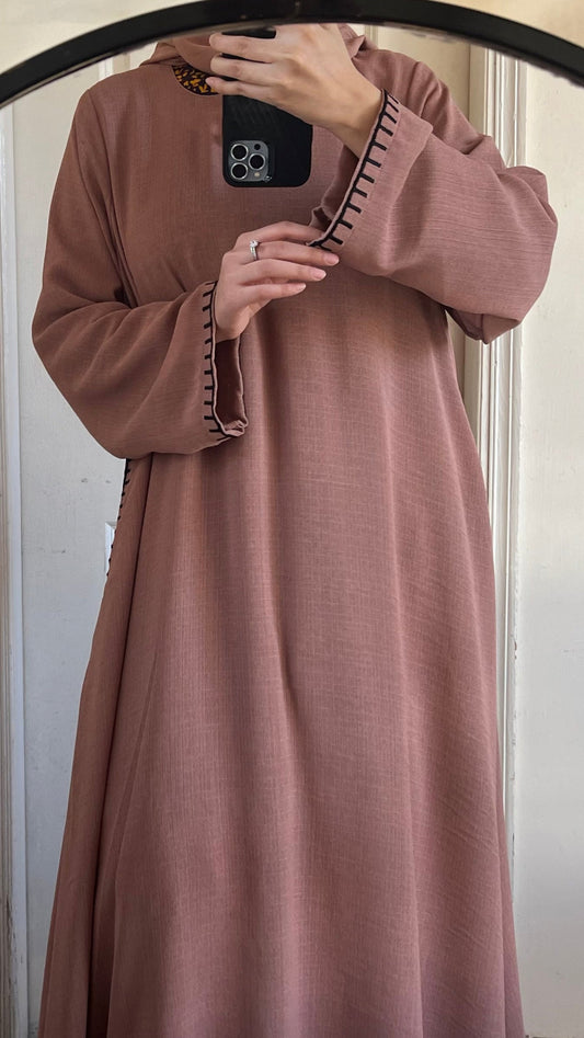 Person wearing a long brown dress taking a mirror selfie.