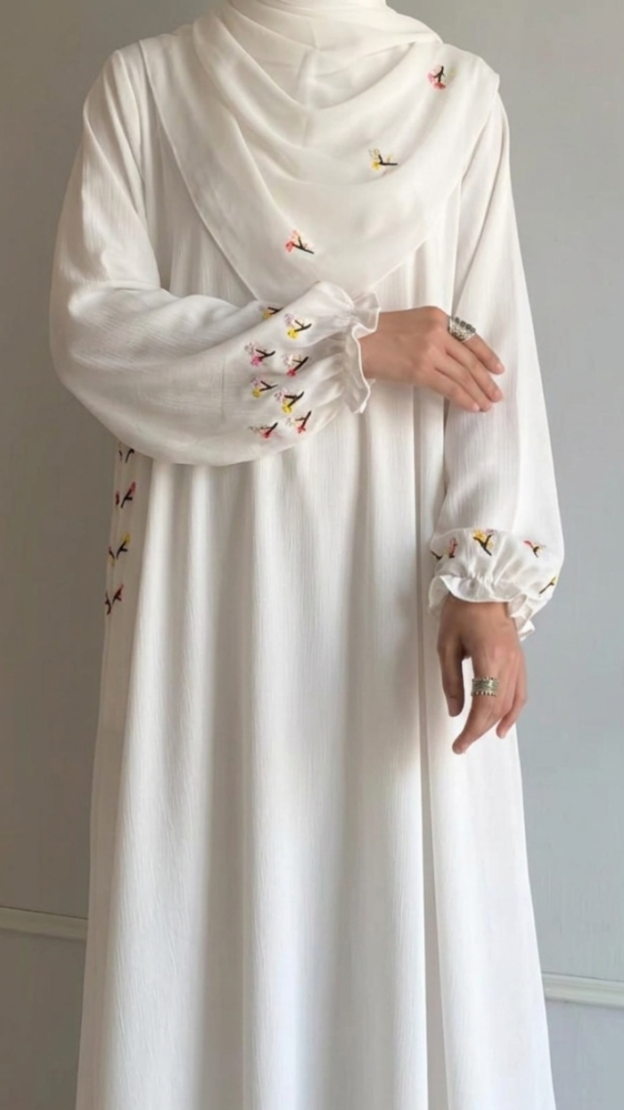 White dress with embroidered details on a plain background